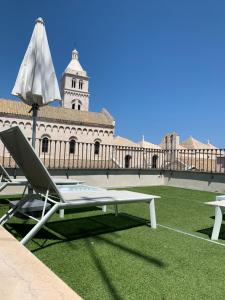 una silla y una sombrilla en el césped frente a un edificio en Sebèl Luxury Rooms, en Barletta