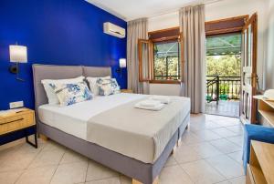 a bedroom with a bed with blue walls and a window at Studios Panagiotas House Astris in Astris
