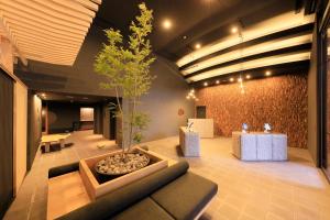 a lobby with a tree and a couch and tables at Merveille Hakone Gora in Hakone