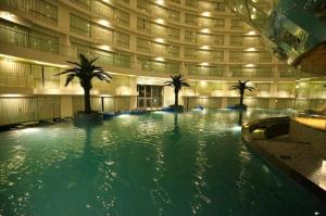 a large swimming pool with palm trees in a building at Homestays at Rajhans BELLIZA Near Airport in Surat