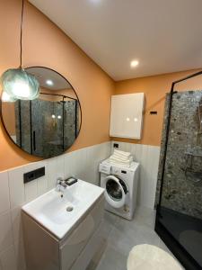łazienka z umywalką i pralką w obiekcie Alėjos Apartmentai City w Druskienikach