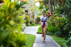 uma mulher a andar por um jardim com uma bandeja de comida em Villa Mandi Ubud em Ubud