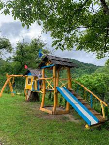 a playground with a house and a slide at Nad Cheremoshem in Tyudov