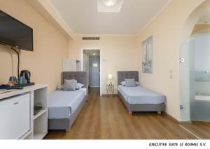 a hotel room with two beds and a flat screen tv at OLYMPOS BEACH HOTEL in Faliraki