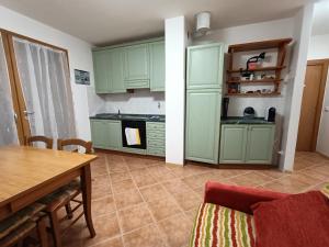 Prada的住宿－Maison Gregory，厨房配有绿色橱柜、桌子和用餐室。