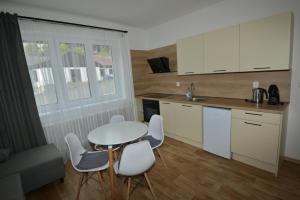 cocina con mesa, sillas blancas y mesa en Apartmány u Pešlů en Železná Ruda