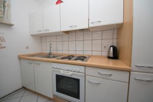 a kitchen with white cabinets and a stove and a sink at House Ursić in Brela +29 photos