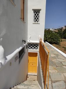 una porta gialla sul lato di una casa bianca di Aigaio Studios tinos a Città di Tinos