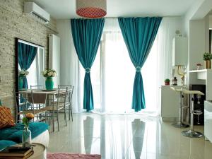 a living room with blue curtains and a table with chairs at Style apartment in Mamaia Nord