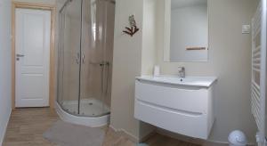 a white bathroom with a sink and a shower at Maślany Domek in Sokolec