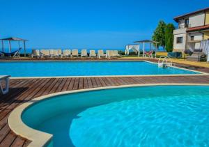 uma grande piscina azul com um deque de madeira em Black Sea Rama Golf and Villas, Bell Tower Villa em Balchik