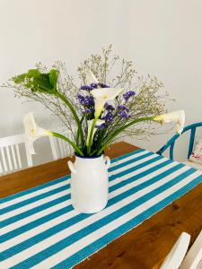 un vaso bianco con fiori viola su un tavolo di Casa Dora: Tradicional y al borde del mar. a Poris de Abona