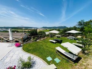 einen Hinterhof mit Liegestühlen und Sonnenschirmen auf dem Gras in der Unterkunft Villa Poggio Ulivo Pool-Apartments in Rivoli Veronese