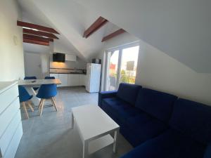 a living room with a blue couch and a kitchen at Pokoje Gościnne Bosman in Białogóra