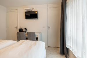 a bedroom with a bed and a desk with a television at The Palmtree in Zandvoort