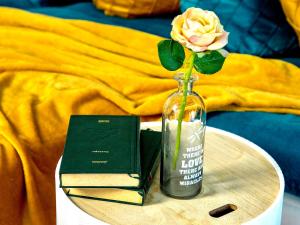 a rose in a vase on a table with a book at Style apartment in Mamaia Nord