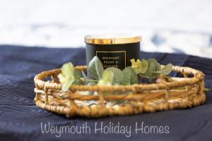 a wicker basket with a candle and a cup at 2021 2 Bedroom Deluxe Caravan Sleeps 6 with WI-FI in Wyke Regis