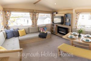 a living room with a couch and a tv at 2021 2 Bedroom Deluxe Caravan Sleeps 6 with WI-FI in Wyke Regis