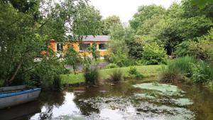 una casa sentada al lado de un estanque con un barco dentro en Ker jolly Maison au cadre naturel sans vis à vis, en Plouégat-Guérand