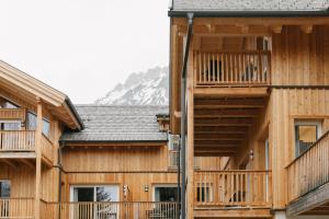 a group of wooden buildings with a mountain in the background at Chalet Village by Apart4you in Ramsau am Dachstein