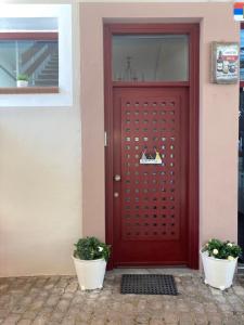 a red door with two potted plants in front of it at sidestory in Limenaria