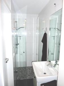 La salle de bains blanche est pourvue d'un lavabo et d'une douche. dans l'établissement Seebox Appartment 3, à Norderney