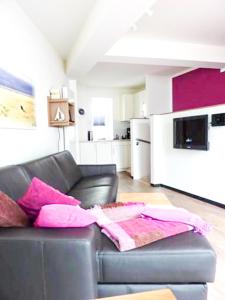 - un salon avec un canapé en cuir noir et des oreillers roses dans l'établissement Seebox Appartment 3, à Norderney