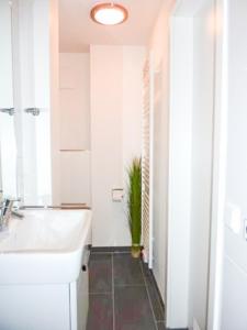 La salle de bains blanche est pourvue d'un lavabo et d'une plante. dans l'établissement Seebox Appartment 3, à Norderney