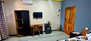 a room with a bedroom with a desk and a television at Kikis Court Resort in Hohoe