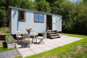 ein kleines Haus mit einer Terrasse, einem Tisch und Stühlen in der Unterkunft Little Idyll shepherds hut in Chester