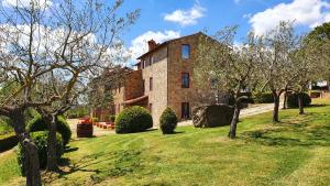 a large brick house with trees in front of it at Vacanze Sant Andrea in Paciano