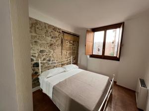 sypialnia z łóżkiem i kamienną ścianą w obiekcie La Rupe Apartments Tropea w Tropei