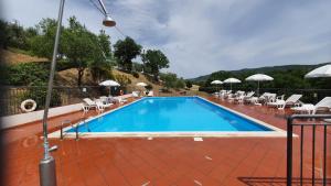 a swimming pool with chairs and umbrellas next to it at Vacanze Sant Andrea in Paciano