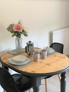 a wooden table with a vase of flowers on it at The Dairyman Suite in Dorchester