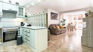 a kitchen with white cabinets and a living room at KORALLIA GUESTHOUSE Castle Harbour in Los Cristianos