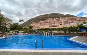 a large swimming pool in front of a large building at KORALLIA GUESTHOUSE Castle Harbour in Los Cristianos