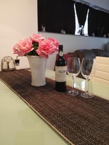 un tavolo con una bottiglia di vino e un vaso con rose rosa di Вила Полина a Varna