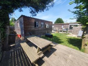 a wooden deck with a picnic table in a yard at Chalet au cœur de la foret de Rambouillet in Les Bréviaires