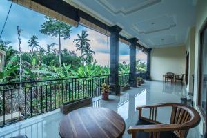 a room with a balcony with a table and chairs at Saputra Guesthouse in Ubud