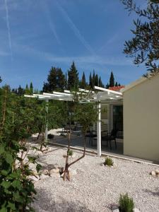 a patio with a white pergola next to a house at Apartman LUCIJA in Korčula