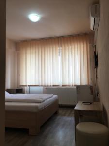 a bedroom with a bed and a window with curtains at Cazare Hofmann in Arad