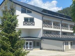 an apartment building with a balcony and a tree at Apartmán Klára in Terchová