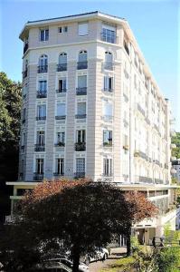 wysoki biały budynek z drzewem przed nim w obiekcie Grand studio 38m2 dans ancien palace avec piscine et place de parking privée w Aix-les-Bains