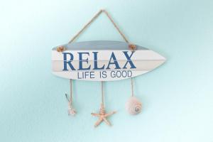 a surfboard hanging on a wall with the words relax life is good at El Greco Nei Pori in Nei Poroi