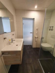 uma casa de banho com um lavatório, um chuveiro e um WC. em Ferienwohnung Relax em Tettnang