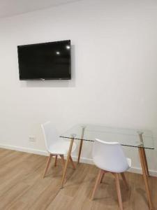 a glass table with two chairs and a television on a wall at Villas Camargo.suites in Camargo