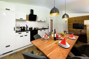 una cocina y comedor con una mesa de madera con sombreros rojos. en Apartment Melina, en Neukirchen am Großvenediger