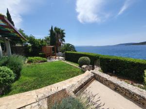 a garden with a stone pathway next to the water at Beach Apartment More in Seget Vranjica