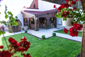 a house with a garden with red flowers in the foreground at Villa DEA DORATA in Oradea