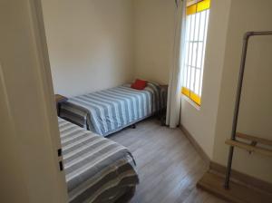 een kleine kamer met twee bedden en een raam bij Wind Puerto Madryn in Puerto Madryn